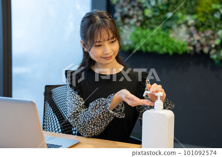 一位女士在辦公桌前消毒雙手 一位女士在辦公桌前消毒雙手 101092574