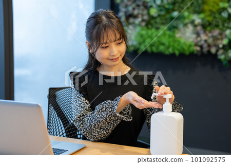 一位女士在辦公桌前消毒雙手 101092575