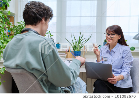 Female education center worker talking to young male college student Female education center worker talking to young male college student 101092670