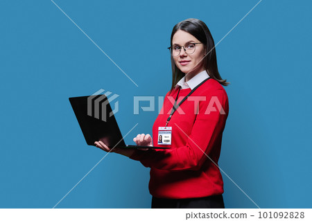 Young woman with educational center badge laptop on blue background Young woman with educational center badge laptop on blue background 101092828