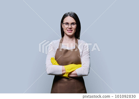 Young woman in rubber glove apron with crossed arms on grey background Young woman in rubber glove apron with crossed arms on grey background 101092830