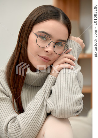Portrait of a young calm woman in glasses looking through glasses at the camera, shot of a young business woman in glasses, stylish glasses fashion accessory 101093186