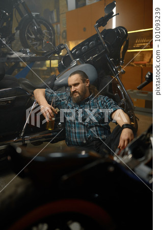 Serious biker sitting on floor and thinking searching way to repair motorcycle 101093239