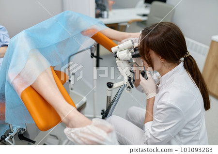 Gynecologist examining patient on chair with gynecological equipment 101093283