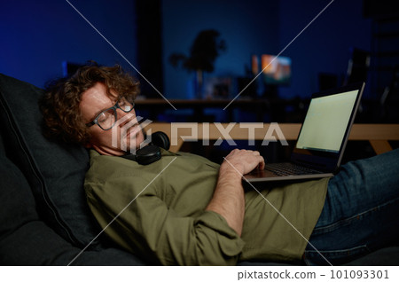 Tired system administrator sleeping under laptop computer on sofa at server room 101093301