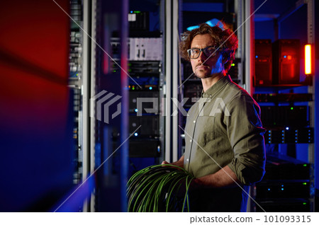 Data center engineer with many optic wires cables walking next to computer racks 101093315