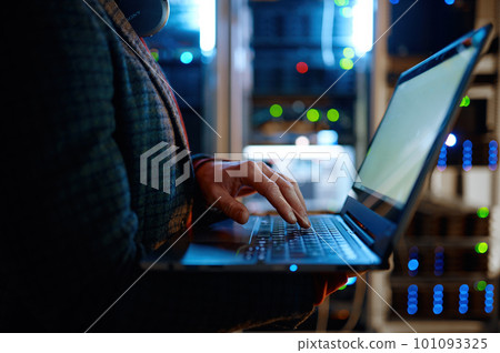 IT technician checking the servers vitals using laptop computer IT technician checking the servers vitals using laptop computer 101093325