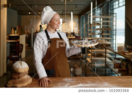 Pastry chef presenting freshly baked cookies standing at bakery kitchen 101093368