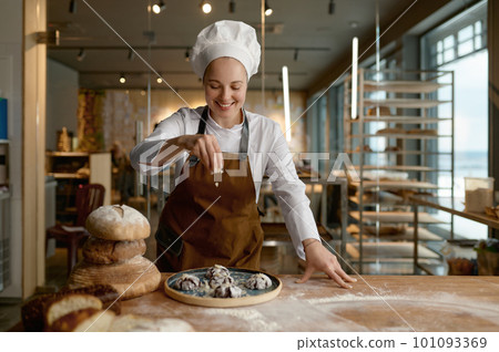 Baker chef sprinkling freshly baked oatmeal cookies with cereals 101093369
