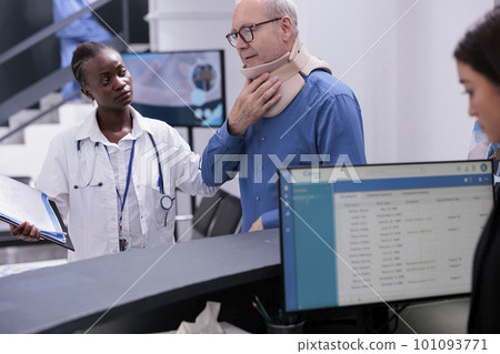 Senior patient with neck collar explaining symptoms to physician doctor asking for painkillers in hospital waiting area. Injured man with cervical foam waiting to attend checkup visit consultation 101093771