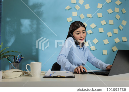 Active female businesswoman talking on mobile phone while using laptop in office. Busy employee finishing online report and attending financial manager call. manager call. Active female businesswoman talking on mobile phone while using laptop in office. Busy employee finishing online report and attending financial manager call. manager call. 101093786