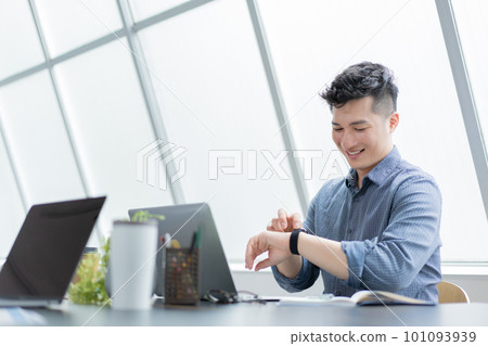 A young man who cares about the time while operating a laptop in the office A young man who cares about the time while operating a laptop in the office 101093939
