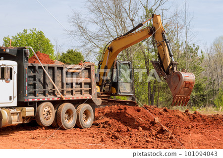 Loading earth into dump truck on construction site with an excavator Loading earth into dump truck on construction site with an excavator 101094043
