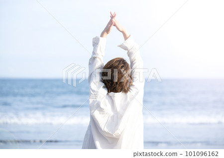 A woman who takes a deep breath and stretches on a sandy beach Stress free 101096162