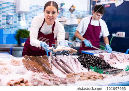 Positive saleswoman demonstrating calamary in fish store 101097063