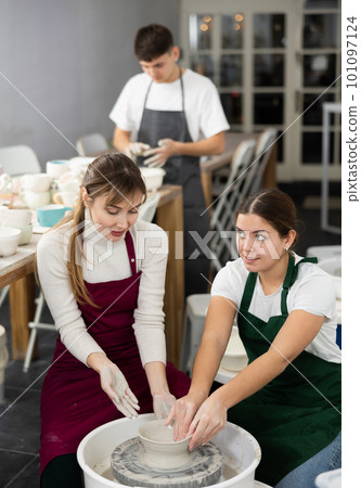 Two young women sculpt product on potter's wheel Two young women sculpt product on potter's wheel 101097124