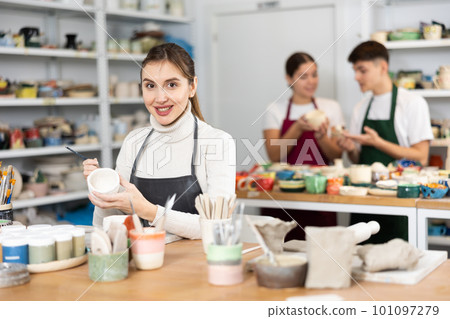 Woman painting with brush on handmade clay cup Woman painting with brush on handmade clay cup 101097279