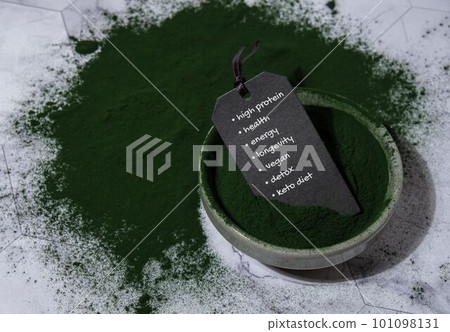 Blue-green algae Chlorella and spirulina powder in bowl with paper note text benefits HIGH PROTEIN HEALTH ENERGY LONGEVITY VEGAN DETOX KETO DIET. Super powder. Natural supplement of algae. Detox 101098131