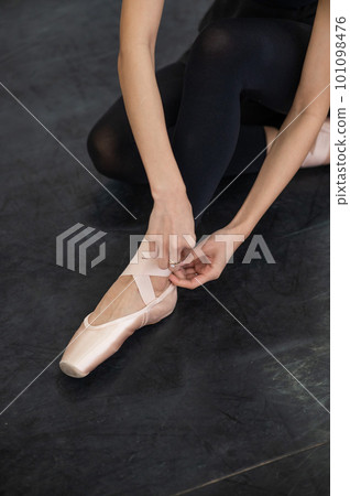 A faceless woman puts on pointe shoes. Close-up of ballerina's legs. A faceless woman puts on pointe shoes. Close-up of ballerina's legs. 101098476