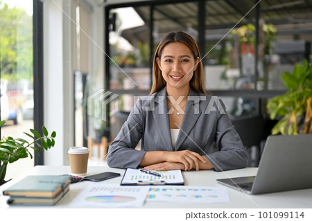 Attractive Asian businesswoman or female boss in formal business suit sits at her desk 101099114