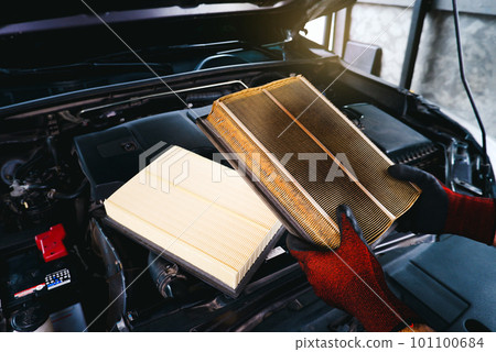 Auto mechanic checking the clogged air filter of a car 101100684