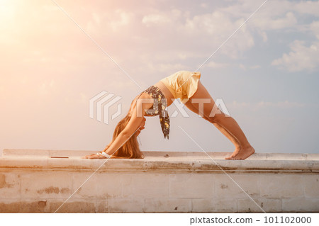 Woman park yoga. Side view of free calm bliss satisfied woman with long hair standing in morning park with yoga position against of sky by the sea. Healthy lifestyle outdoors in park, fitness concept. Woman park yoga. Side view of free calm bliss satisfied woman with long hair standing in morning park with yoga position against of sky by the sea. Healthy lifestyle outdoors in park, fitness concept. 101102000