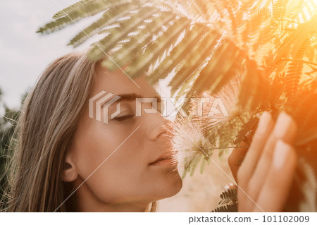 Beauty portrait of happy woman closeup. Young girl smelling Chinese acacia pink blossoming flowers. Portrait of young woman in blooming spring, summer garden. Romantic vibe. Female and nature 101102009