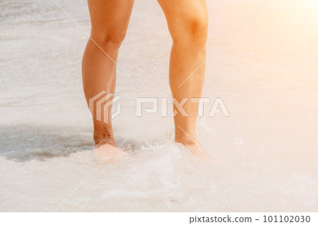 Sea beach travel - woman walking on sand beach leaving footprints in the white sand. Female legs walking along the seaside barefoot, close-up of the tanned legs of a girl coming out of the water. Sea beach travel - woman walking on sand beach leaving footprints in the white sand. Female legs walking along the seaside barefoot, close-up of the tanned legs of a girl coming out of the water. 101102030