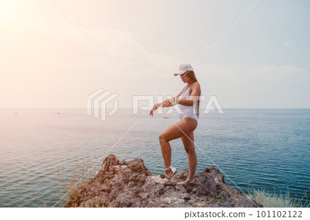 Woman travel sea. Happy tourist in hat enjoy taking picture outdoors for memories. Woman traveler posing on the beach at sea surrounded by volcanic mountains, sharing travel adventure journey Woman travel sea. Happy tourist in hat enjoy taking picture outdoors for memories. Woman traveler posing on the beach at sea surrounded by volcanic mountains, sharing travel adventure journey 101102122