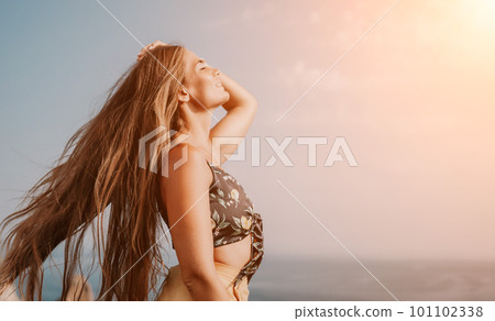 Woman travel sea. Happy tourist taking picture outdoors for memories. Woman traveler looks at the edge of the cliff on the sea bay of mountains, sharing travel adventure journey 101102338