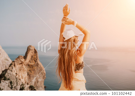Woman travel sea. Happy tourist enjoy taking picture outdoors for memories. Woman traveler looks at the edge of the cliff on the sea bay of mountains, sharing travel adventure journey Woman travel sea. Happy tourist enjoy taking picture outdoors for memories. Woman traveler looks at the edge of the cliff on the sea bay of mountains, sharing travel adventure journey 101102442
