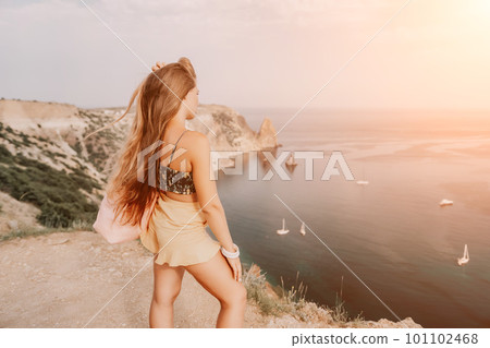 Woman travel sea. Happy tourist taking picture outdoors for memories. Woman traveler looks at the edge of the cliff on the sea bay of mountains, sharing travel adventure journey Woman travel sea. Happy tourist taking picture outdoors for memories. Woman traveler looks at the edge of the cliff on the sea bay of mountains, sharing travel adventure journey 101102468