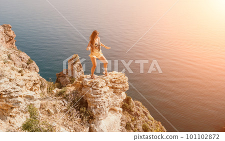 Woman travel sea. Happy tourist enjoy taking picture outdoors for memories. Woman traveler looks at the edge of the cliff on the sea bay of mountains, sharing travel adventure journey Woman travel sea. Happy tourist enjoy taking picture outdoors for memories. Woman traveler looks at the edge of the cliff on the sea bay of mountains, sharing travel adventure journey 101102872