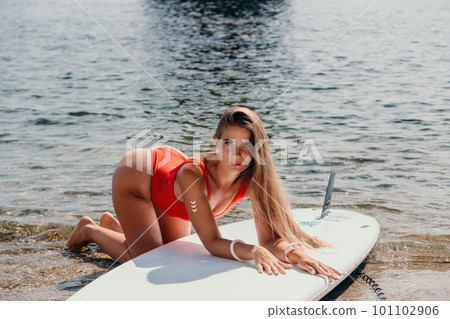 Woman sea sup. Close up portrait of happy young caucasian woman with long hair looking at camera and smiling. Cute woman portrait in bikini posing on sup board in the sea Woman sea sup. Close up portrait of happy young caucasian woman with long hair looking at camera and smiling. Cute woman portrait in bikini posing on sup board in the sea 101102906