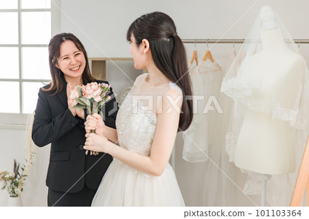 Bride and wedding planner woman trying on and fitting a wedding dress Bride and wedding planner woman trying on and fitting a wedding dress 101103364
