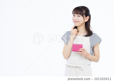 A housewife in her thirties wearing an apron who is worried with a smile holding her wallet A housewife in her thirties wearing an apron who is worried with a smile holding her wallet 101103411