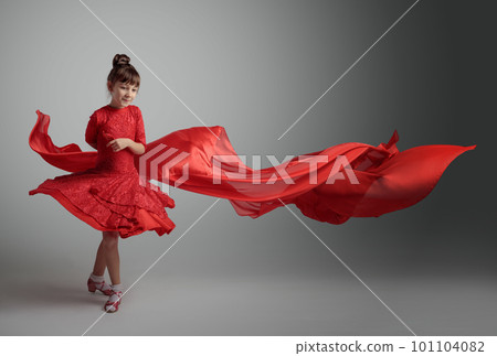 Dancing girl in a red dress with flying red satin fabric. 101104082