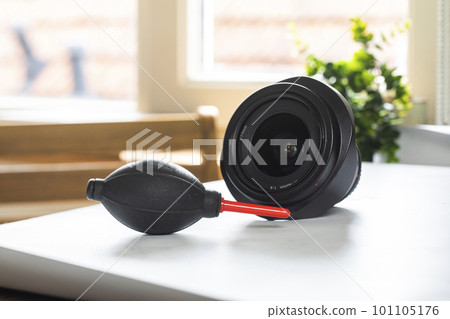 Lens on desk with cleaning tools for DSLR and Mirrorless cameras. Cleaning kit for cmos surface. Air blower, swab, isopropyl alcohol dropper and microfyber cloths. Lens and camera cleaning solution 101105176