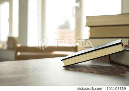 Education learning concept with opening book or textbook at home in office room, stack piles of literature text academic archive on reading desk and aisle of bookshelves in school study class room 101105189
