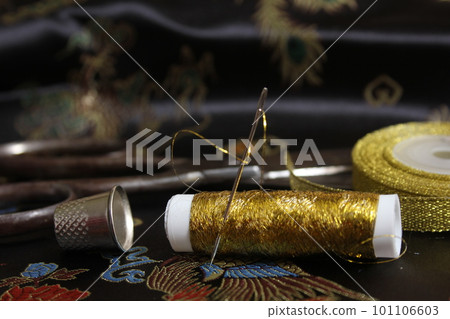 Spool of Gold Thread With Thimble on Vintage Black Silk Fabric Spool of Gold Thread With Thimble on Vintage Black Silk Fabric 101106603