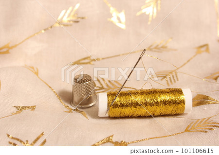 Spool of Gold Thread With Thimble on Metallic Fabric 101106615
