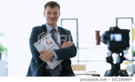 Successful businessman coach with documents with graphs in hands standing near camera in office 101106964