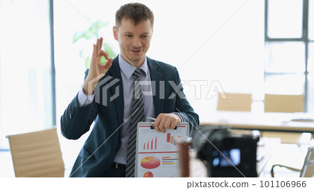 Successful businessman coach with paperwork with graphs in hands showing ok gesture in front of camera in office 101106966