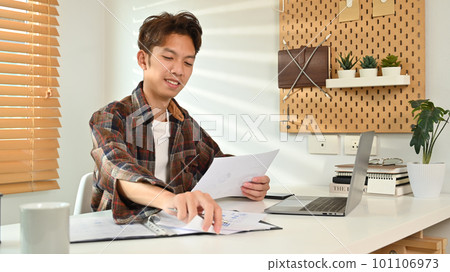 Image of asian male in smart casual wears using laptop at home office. Freelance, distance, education, e-learning concept Image of asian male in smart casual wears using laptop at home office. Freelance, distance, education, e-learning concept 101106973