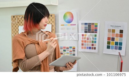Young asian woman designer illustrator standing in modern design studio and using digital tablet Young asian woman designer illustrator standing in modern design studio and using digital tablet 101106975
