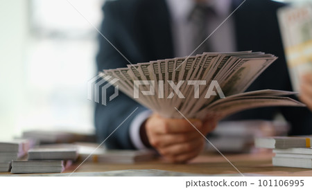Businessman holding fan of money 100 dollar bills in office closeup Businessman holding fan of money 100 dollar bills in office closeup 101106995