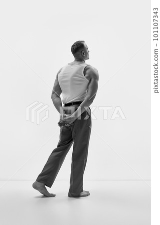 Studio shot of elegant man wearing classic trousers and posing over studio background. Muscular body shape. Black and white Studio shot of elegant man wearing classic trousers and posing over studio background. Muscular body shape. Black and white 101107343