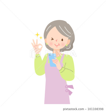 A middle-aged woman in an apron who looks at the screen of her smartphone and gives an OK sign A middle-aged woman in an apron who looks at the screen of her smartphone and gives an OK sign 101108398