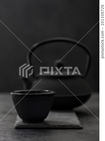 Chinese iron teapot with cup of traditional tea on black background. Chinese iron teapot with cup of traditional tea on black background. 101108726
