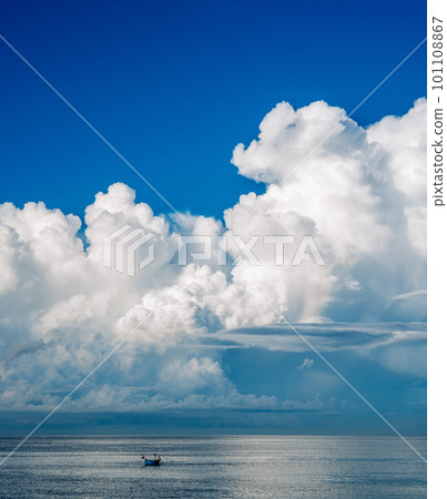 A boat is sailing in the ocean with a large cloud in the sky. 101108867